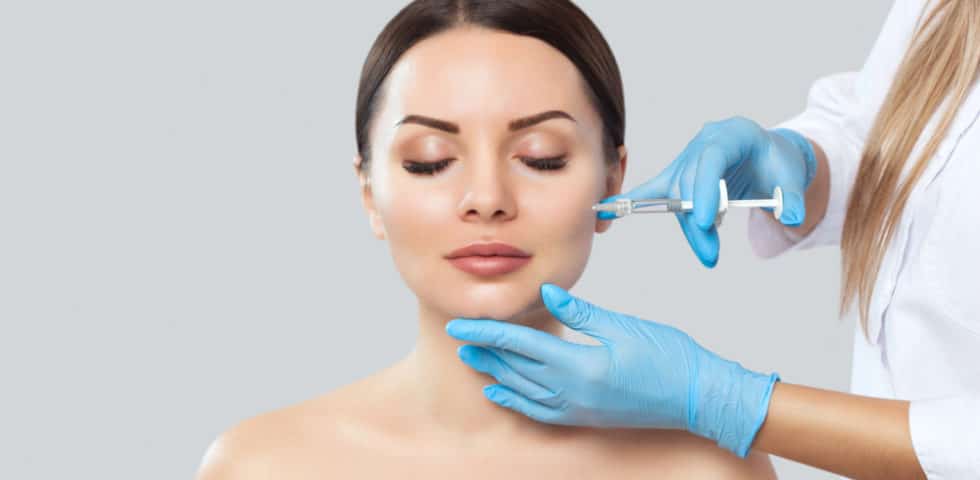 Medical aesthetic professional injecting dermal filler into woman’s cheekbone
