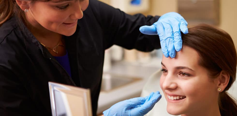 Woman looking in mirror happy with how BOTOX has worked.