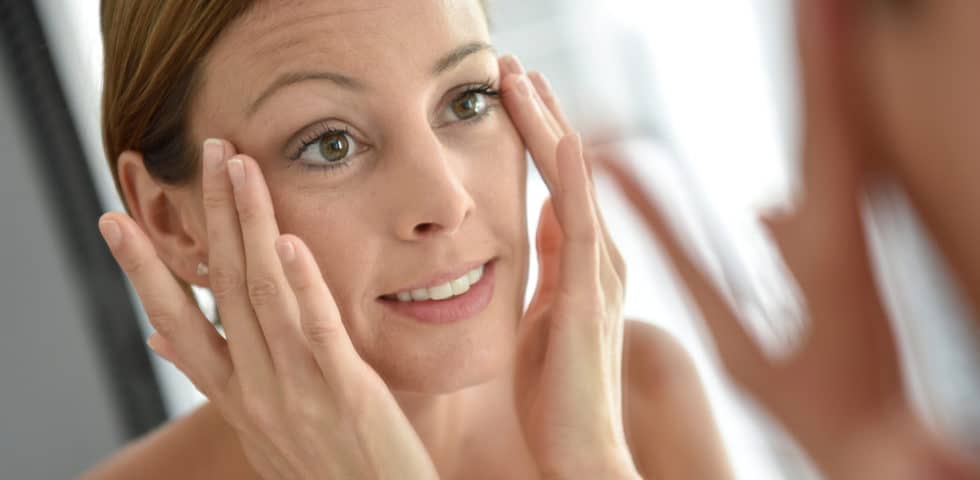 Woman touching her skin after getting rid of wrinkles with wrinkle treatment