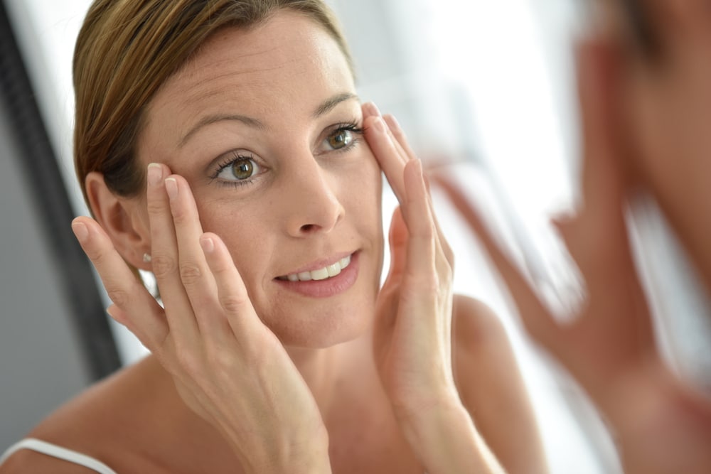 Woman touching her skin after getting rid of wrinkles with wrinkle treatment